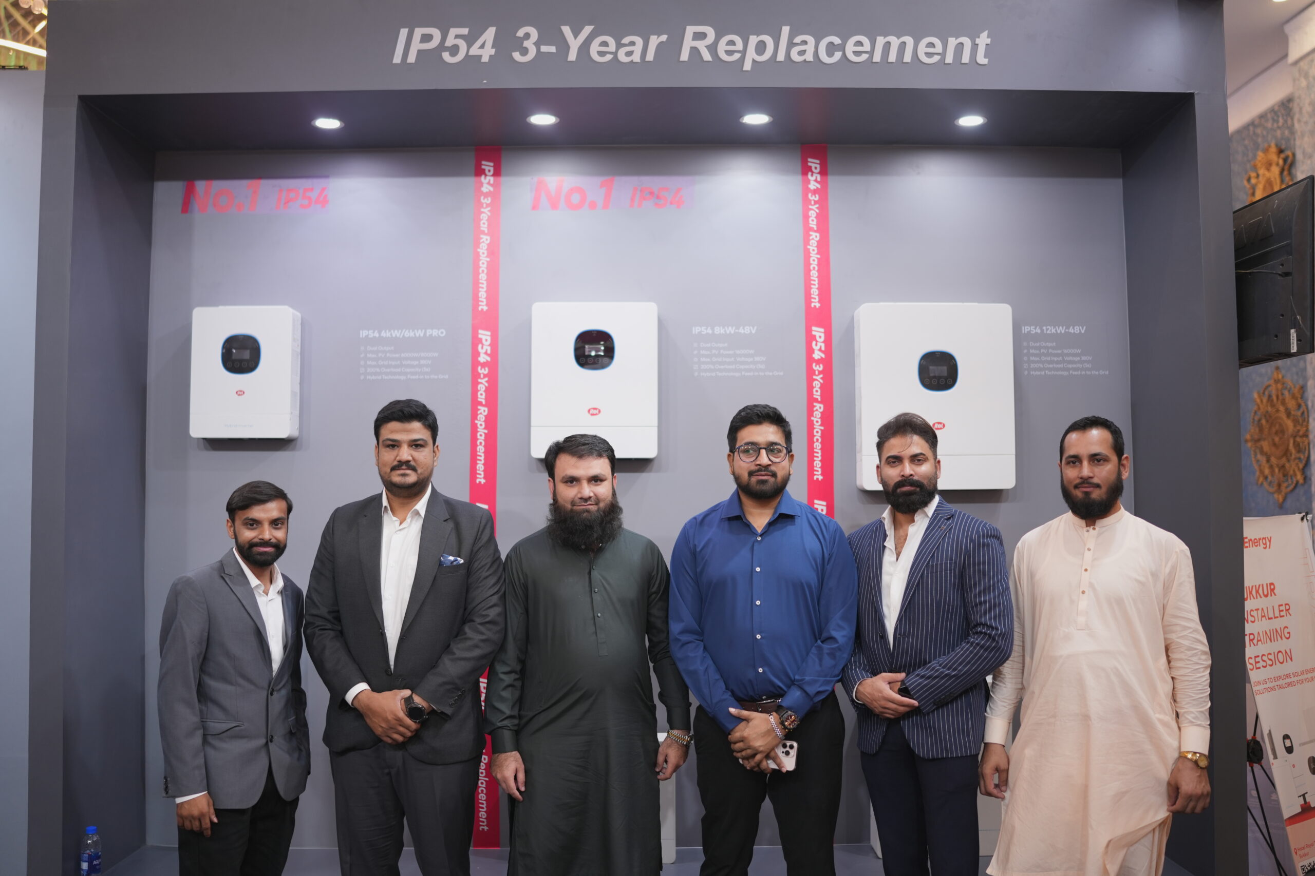itel Energy team and visitors photographed against the custom inverter display wall