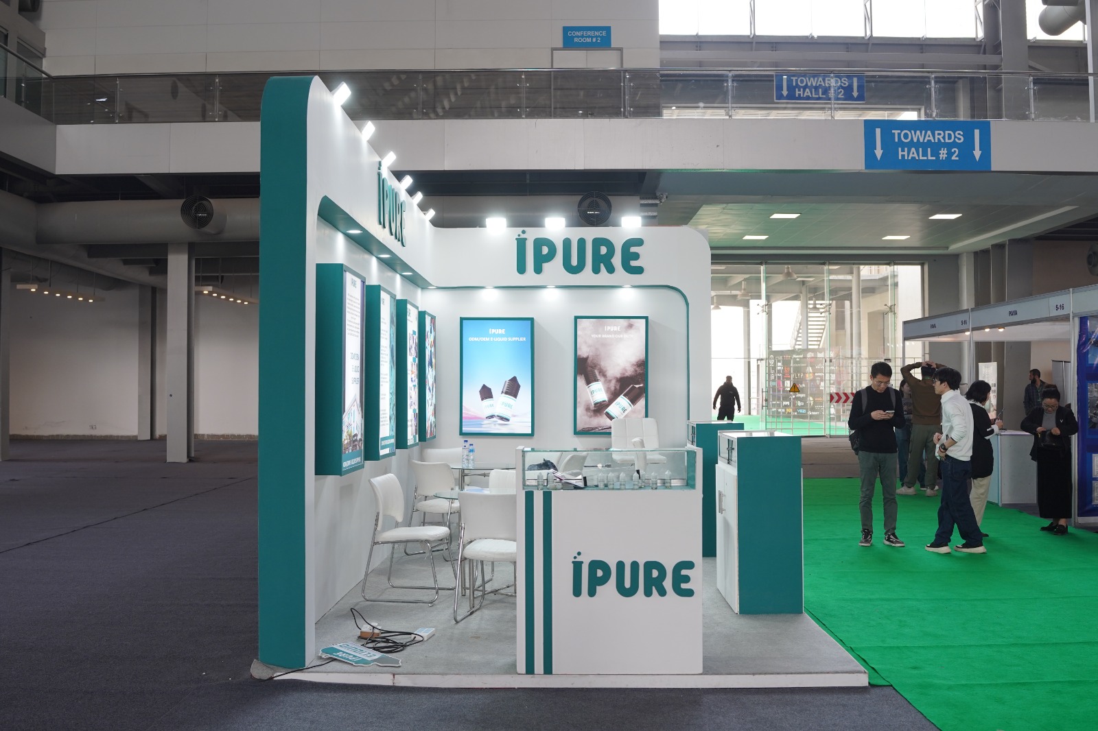 iPURE custom exhibition stand featuring illuminated panels and branded glass showcase counters